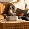 3b43ba0a-029c-4229-87c2-fd56087e27b4 Radio réveil lumineux posé sur une table à côté de quelqu'un qui lit un livre