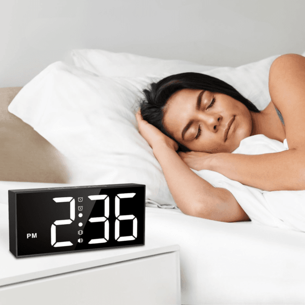 Réveil vibrant devant une femme qui dort