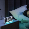 Réveil moderne avec LED bleu allumée sur une table basse devant une femme qui dort