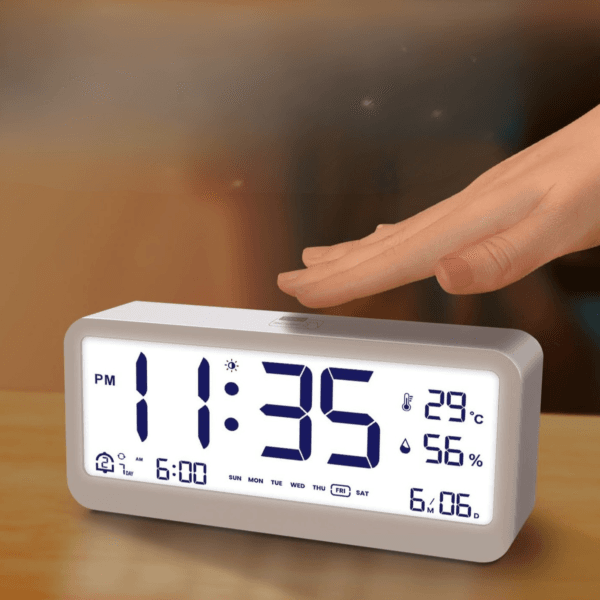 enjfbdbjsdfvdfd Réveil blanc sur une table avec une main au dessus qui appuie sur son bouton