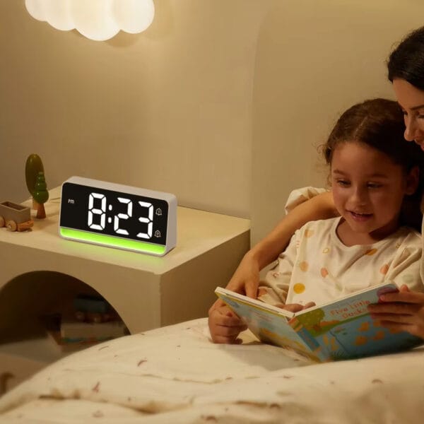 Réveil moderne avec led verte devant une femme qui raconte une histoire à sa fille
